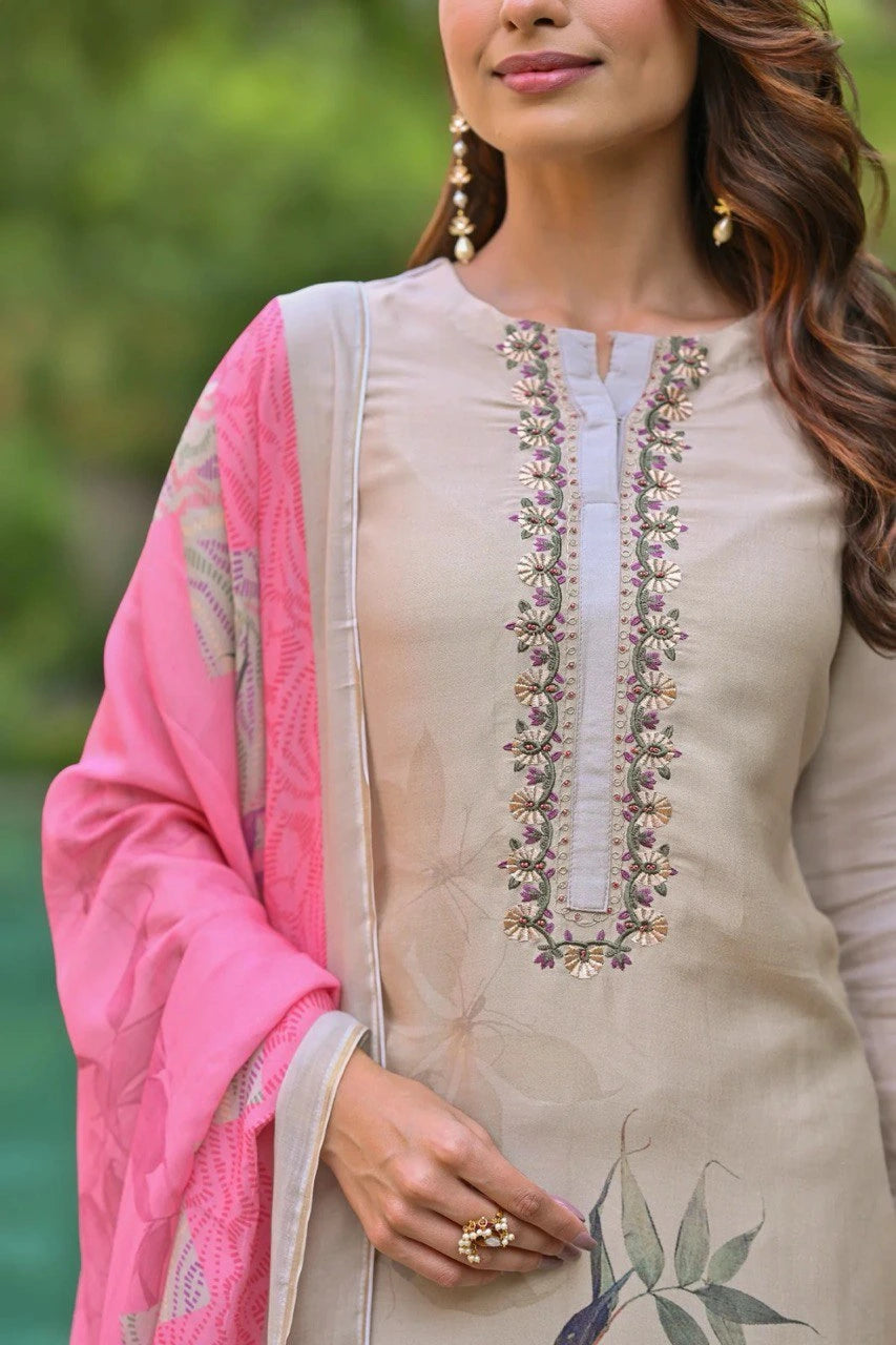 Woman wearing a beige embroidered outfit with a pink dupatta, outdoors.